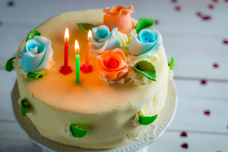 用蜡烛和玫瑰装饰的生日蛋糕