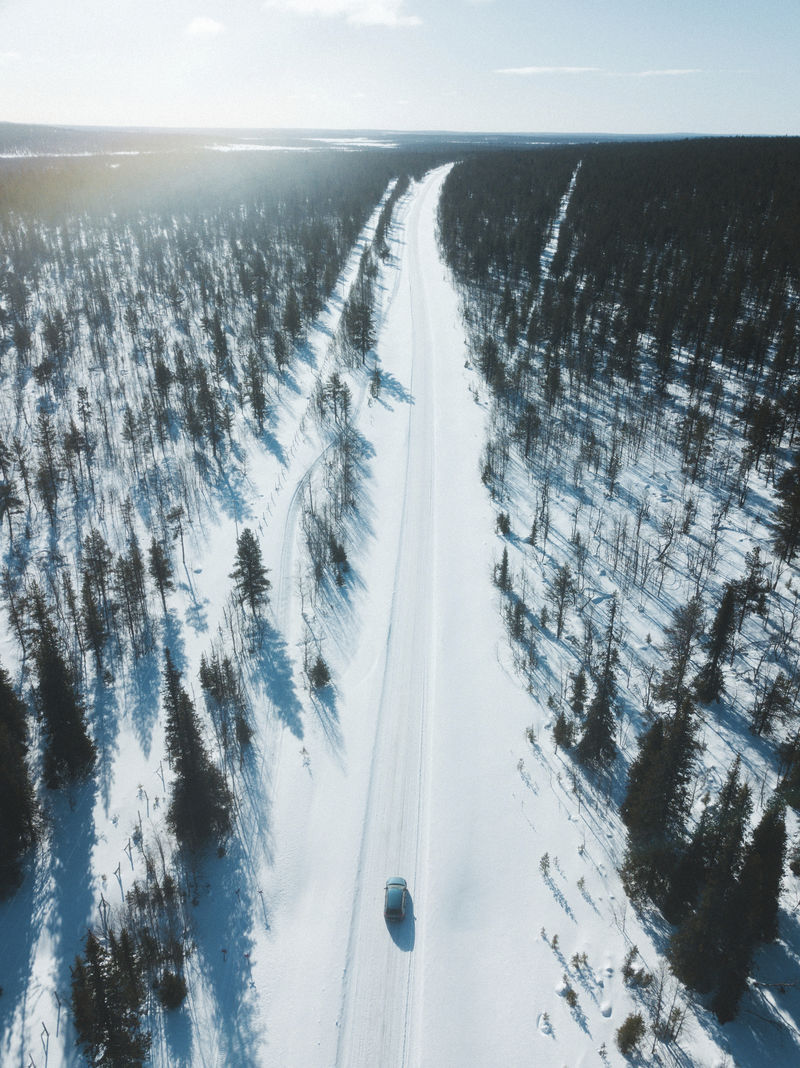 车辆行驶在树林间积雪覆盖的道路上