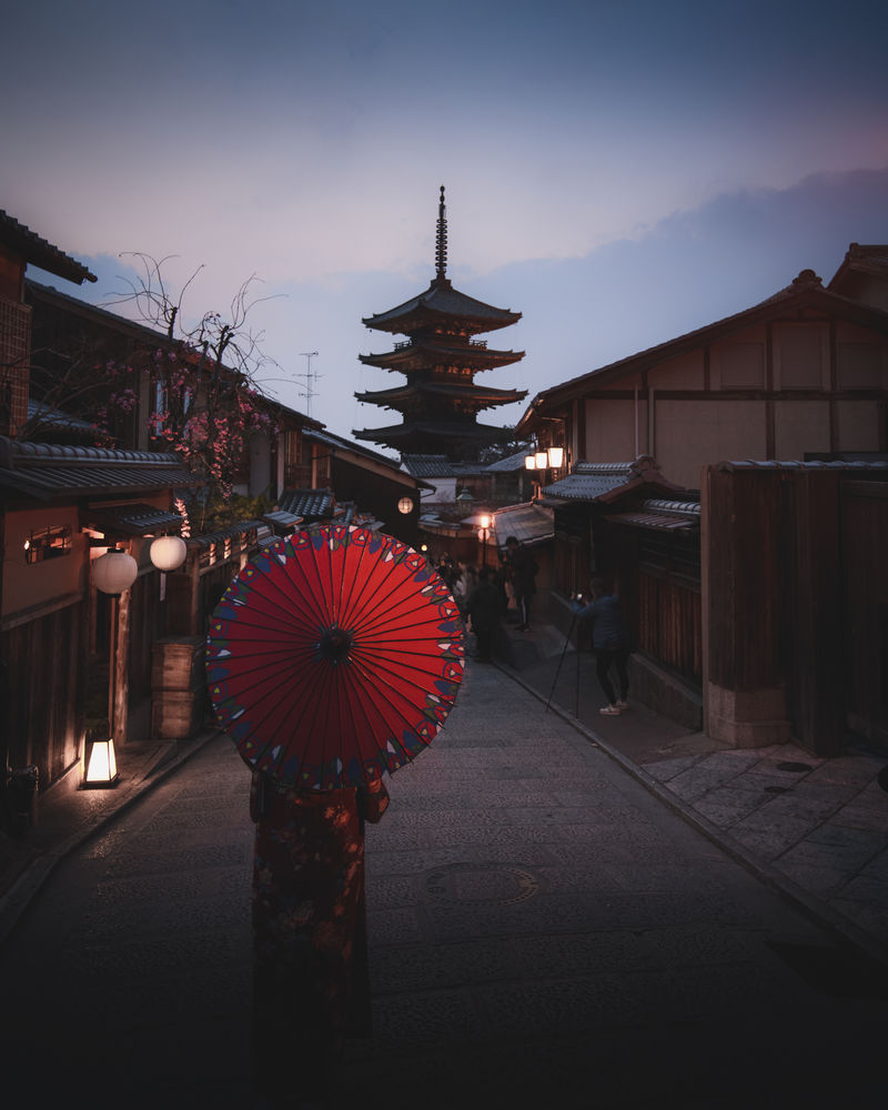 在日本京都的靖坂宝塔一个穿着和服的女人拿着一把红伞走着