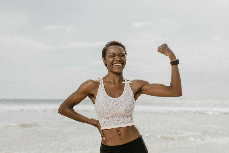 快乐的黑人妇女在海边伸展她的肌肉