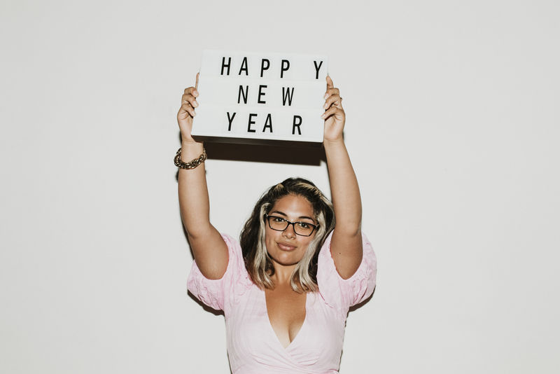 戴眼镜的女人举起新年快乐板