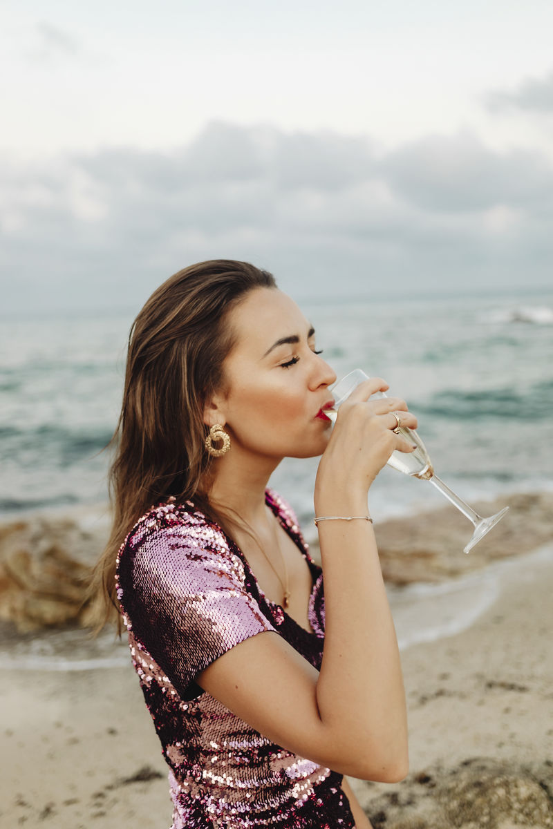 穿着粉红色裙子的女人在海滩上喝着香槟