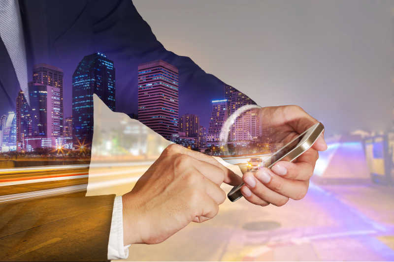 商人使用智能手机和城市夜景的双重曝光