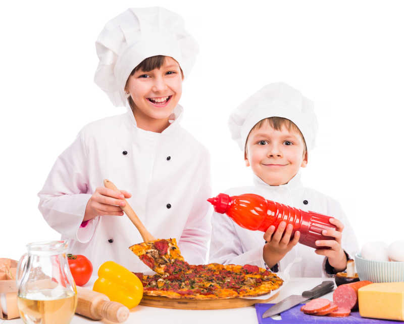两个微笑的小厨师做新鲜的披萨