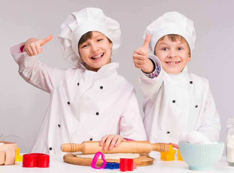 竖起大拇指的两个穿着厨师制服的孩子