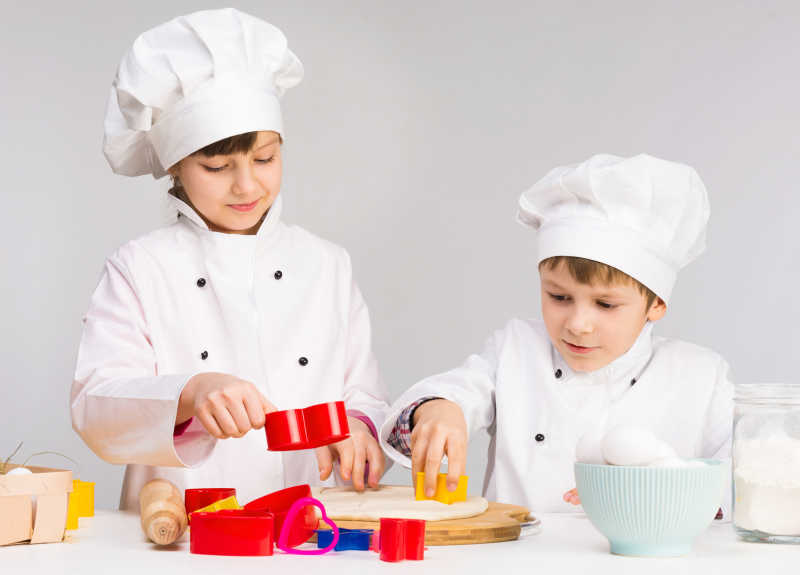 厨房里面带微笑的两个孩子制作面团