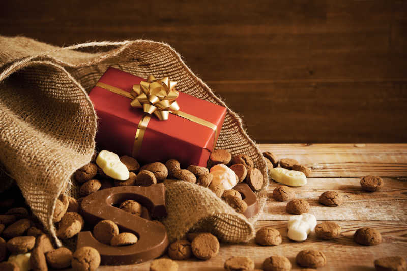 棕色背景下木桌上的巧克力字母糖果和红色礼物盒