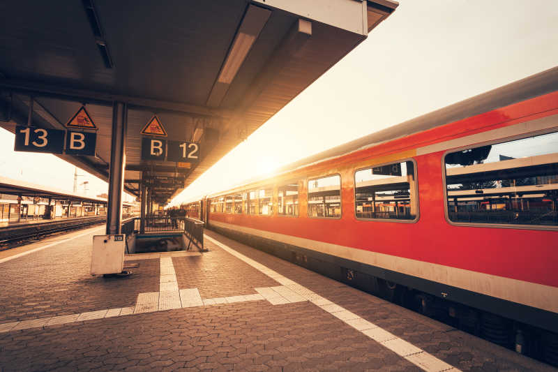 美丽的火车站与现代红色列车在夕阳下的纽伦堡