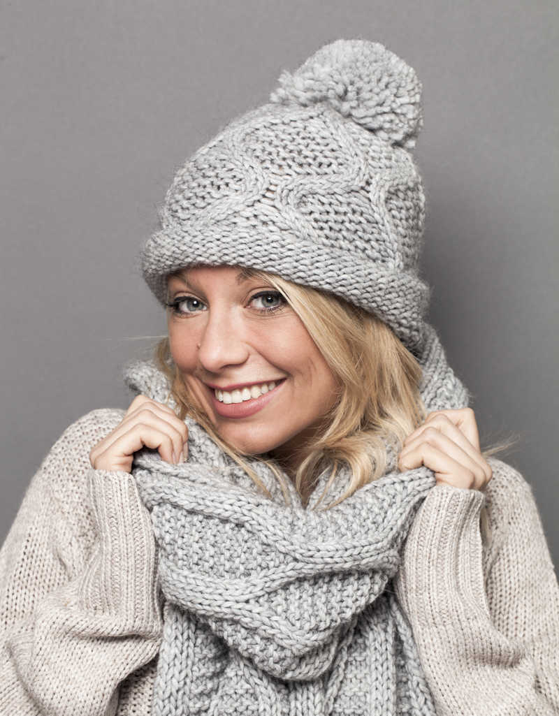时髦温暖的冬天女人戴着她的羊毛围巾与帽子