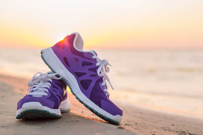 沙滩上的一双紫色运动鞋