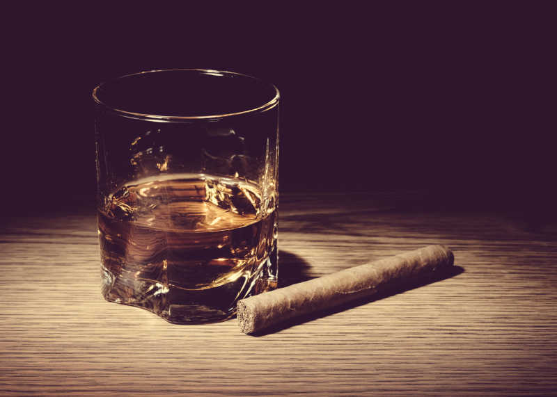 木桌上的雪茄和威士忌玻璃杯