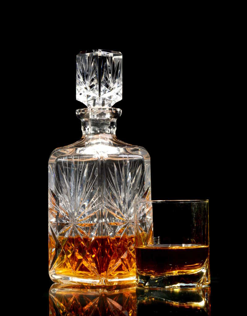黑色背景在玻璃瓶和杯中的威士忌