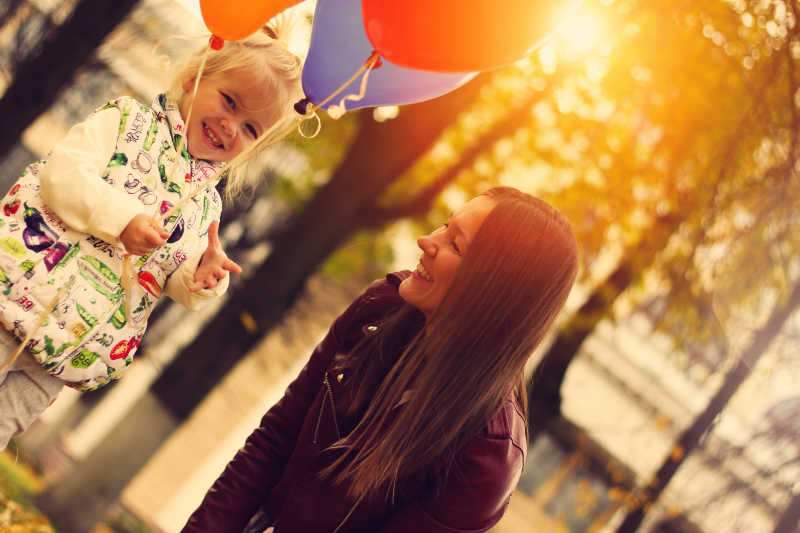 快乐的孩子带着气球在秋天的公园里散步