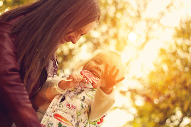 快乐的年轻母亲带着可爱的女儿在公园里
