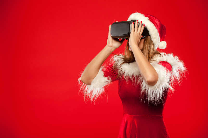 红色背景下戴VR眼镜的圣诞女孩