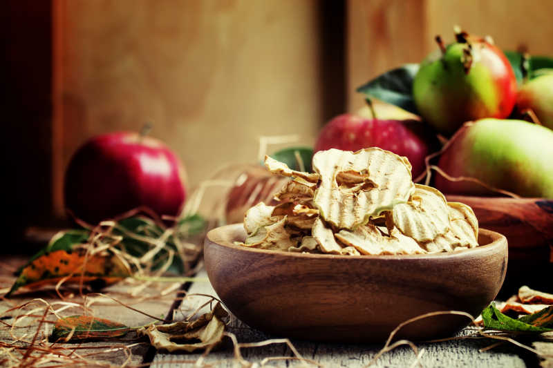 古董木材背景中的新鲜苹果与水果脆片