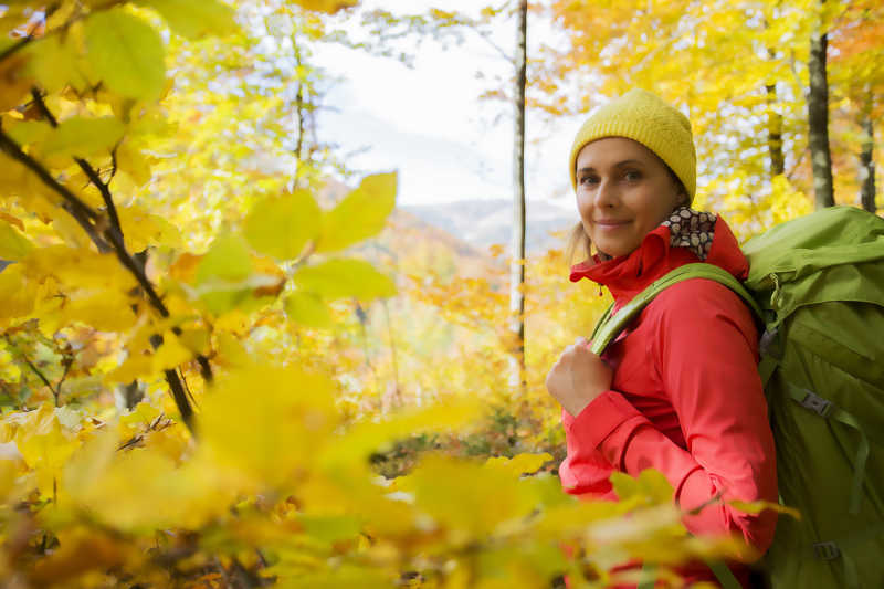 背着黄色包在秋天的山上旅行的女人
