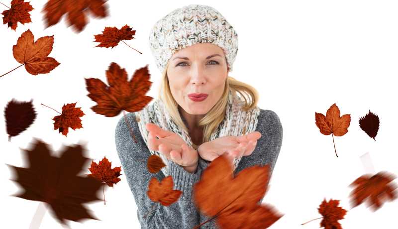 白色背景下保暖的女人肆意吹散树叶