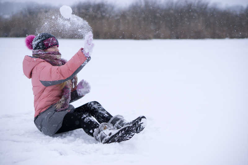 坐在雪地上玩耍的女子