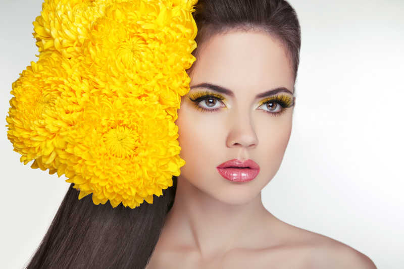 美丽的模特黑色头发上的黄色菊花装饰