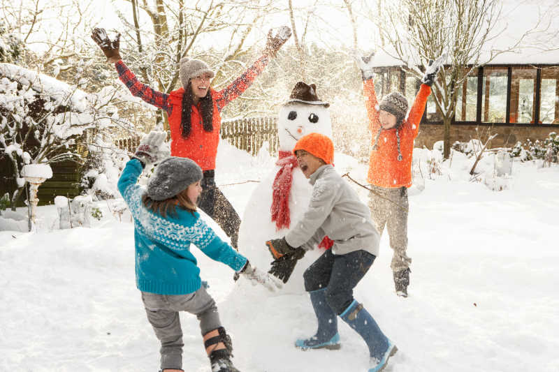 在花园里堆雪人母亲和孩子们