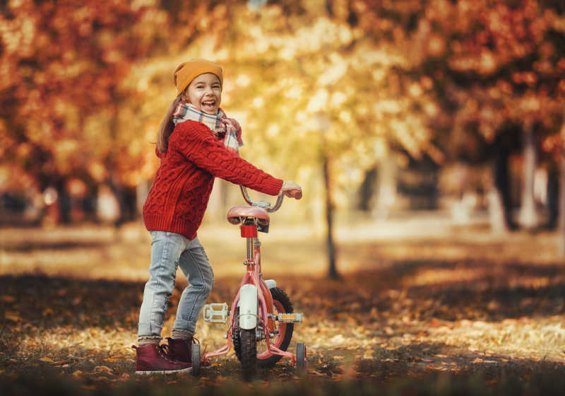 可爱的小女孩推着脚踏车在公园散步
