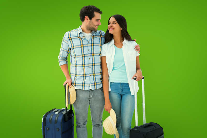 绿色背景下的拉着行李箱的年轻夫妇