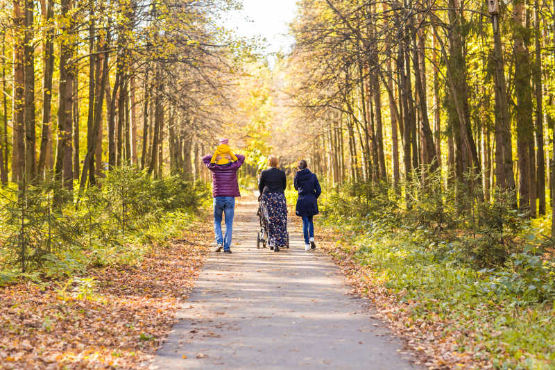 秋季森林小路上正在散步的幸福家庭