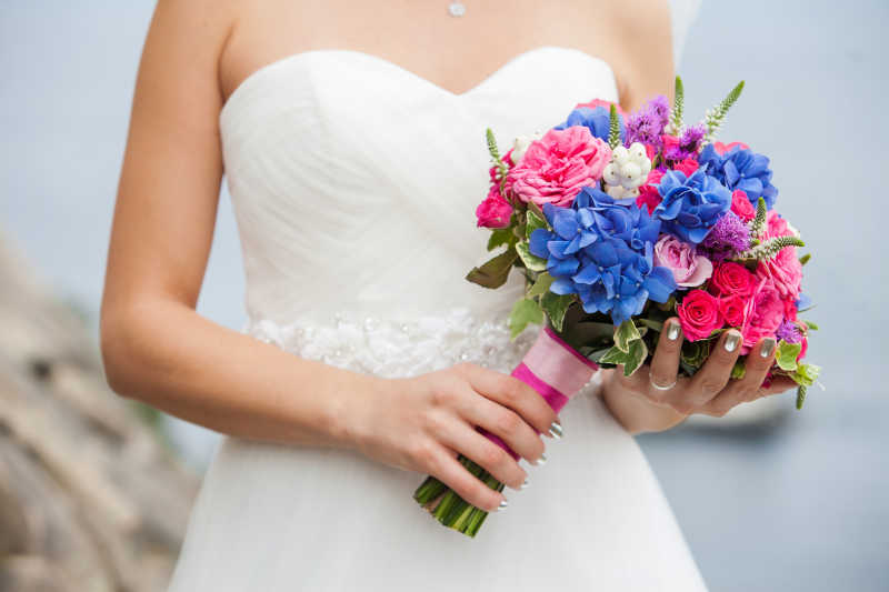 白色背景下新娘手中的美丽婚礼花束