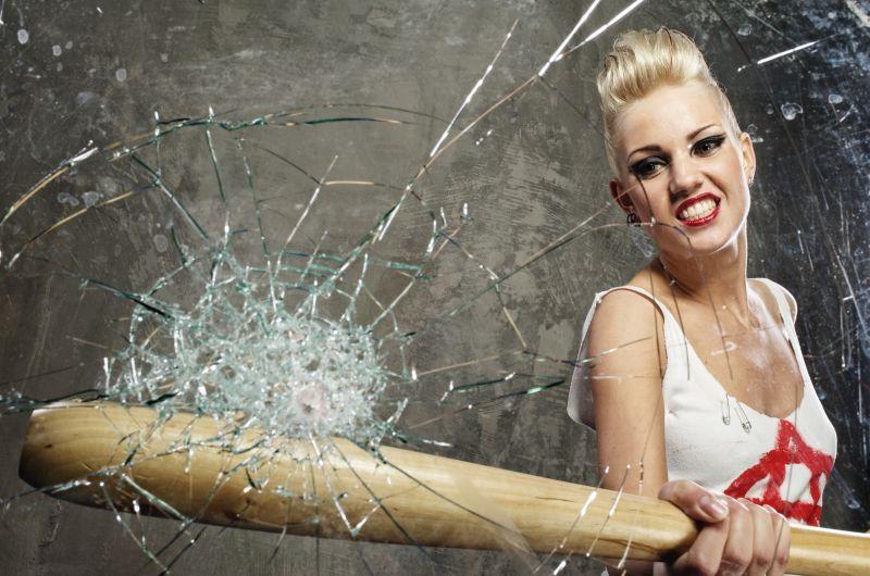 愤怒的女人用木棒打破玻璃
