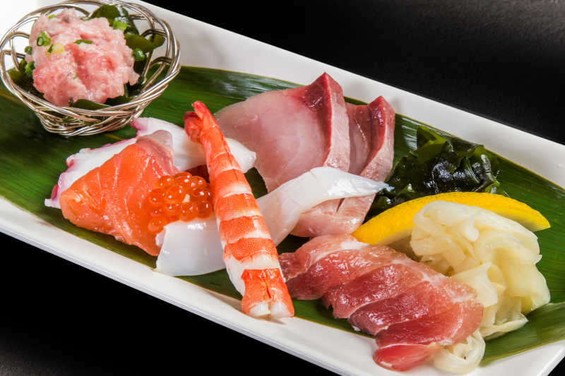 黑色桌上的日本生鱼片和海鲜摆盘
