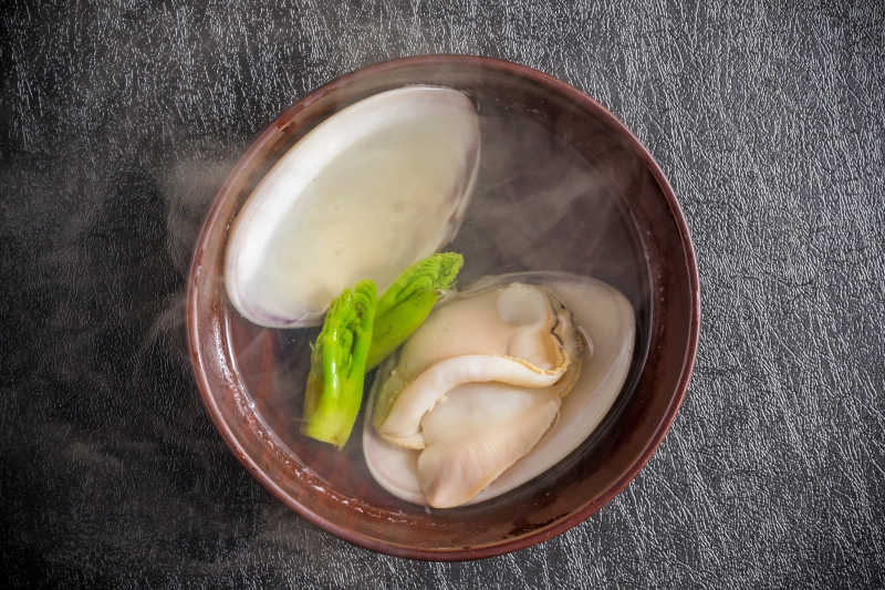 灰色桌上棕色瓷碗里的海鲜蛤蜊海鲜汤