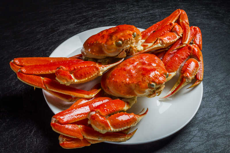 黑色桌上盘子里的红色的被煮熟的螃蟹