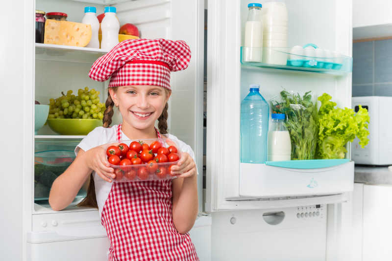 小厨师在冰箱旁拿西红柿