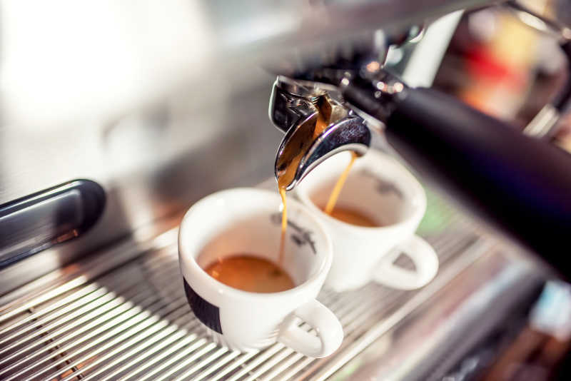 意大利浓咖啡机器将新鲜咖啡倒进餐厅的杯子里