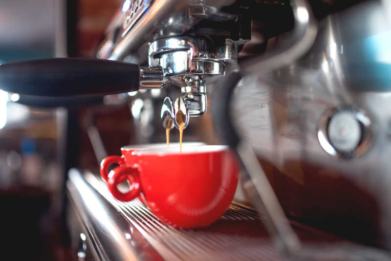 红色杯子在咖啡机下接咖啡
