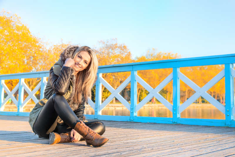秋天公园里坐在地上面带微笑的美女
