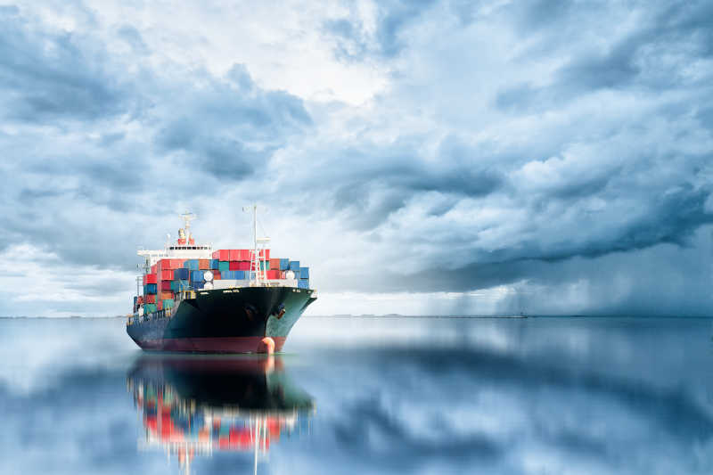 有云的天空背景下水面上的国际集装箱货船