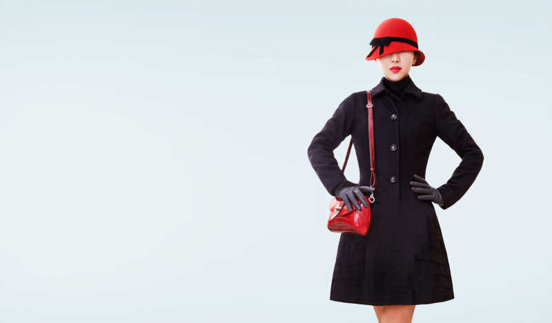 冬天时尚的女人穿着黑色大衣戴着红色毛衣与包包