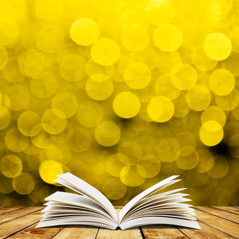 金色光斑背景下木地板上的书本