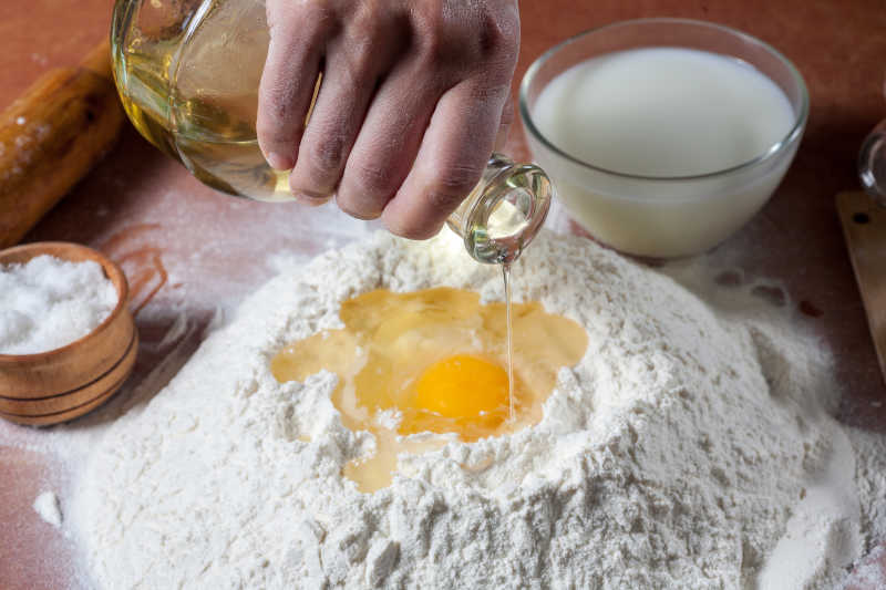 一只手使用鸡蛋和调味料拌和面粉