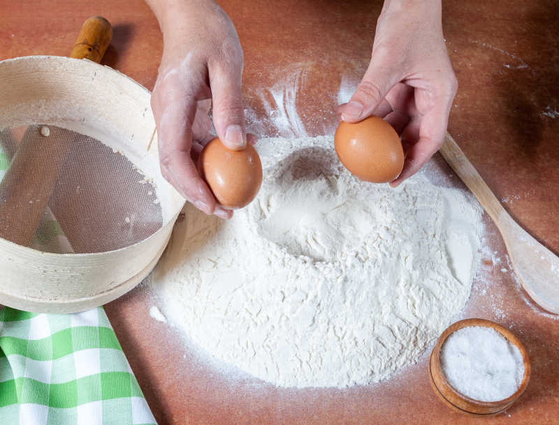 在木桌上使用鸡蛋拌和面粉