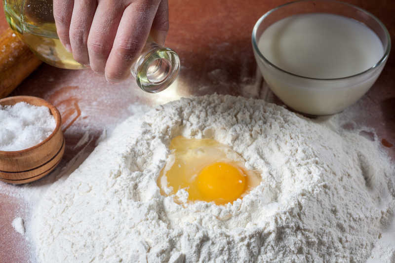 木桌上一只手使用鸡蛋拌和面粉