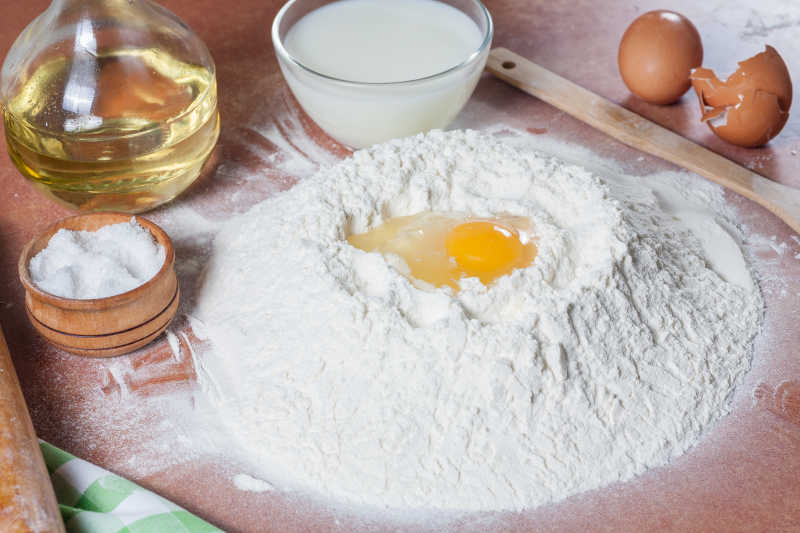 木桌上制作面包时使用鸡蛋拌和面粉
