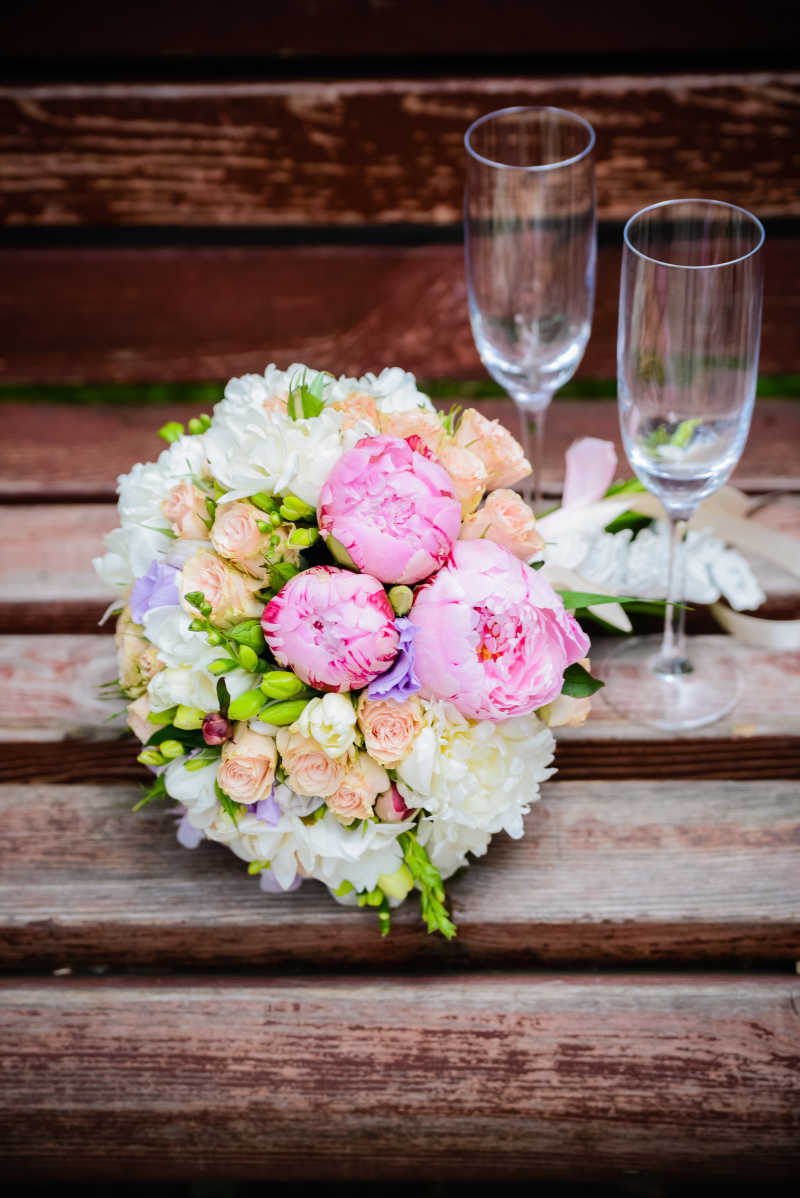 木板上的美丽的新娘捧花与玻璃杯