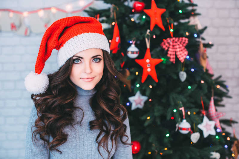 站在圣诞树前微笑的年轻美女