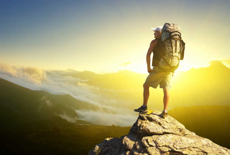 站在在岩石上欣赏风景的登山者游客