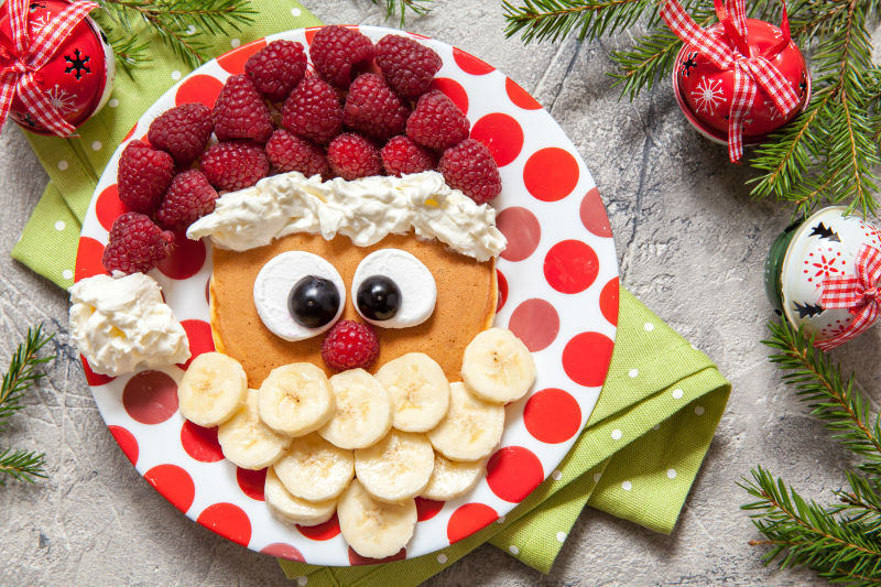 盘子里用热松饼和水果摆成的圣诞老人头