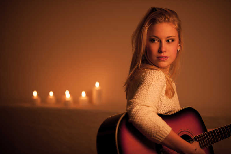 手拿吉他的美女与蜡烛