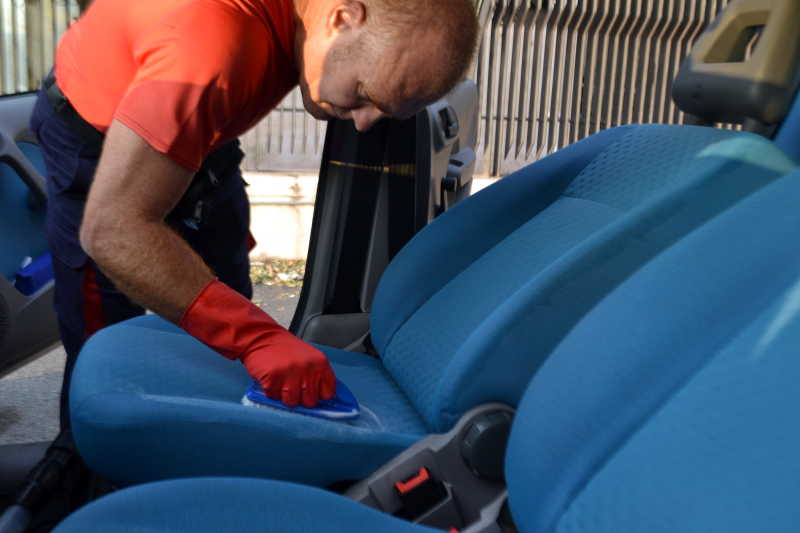 工人拿着刷子清洁蓝色的汽车座椅